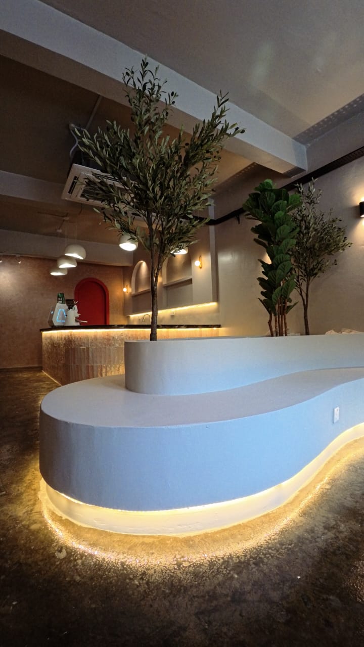 Curved concrete bench with olive tree planter and under-glow lighting at ChaPika Cafe, built by BOSSBINA